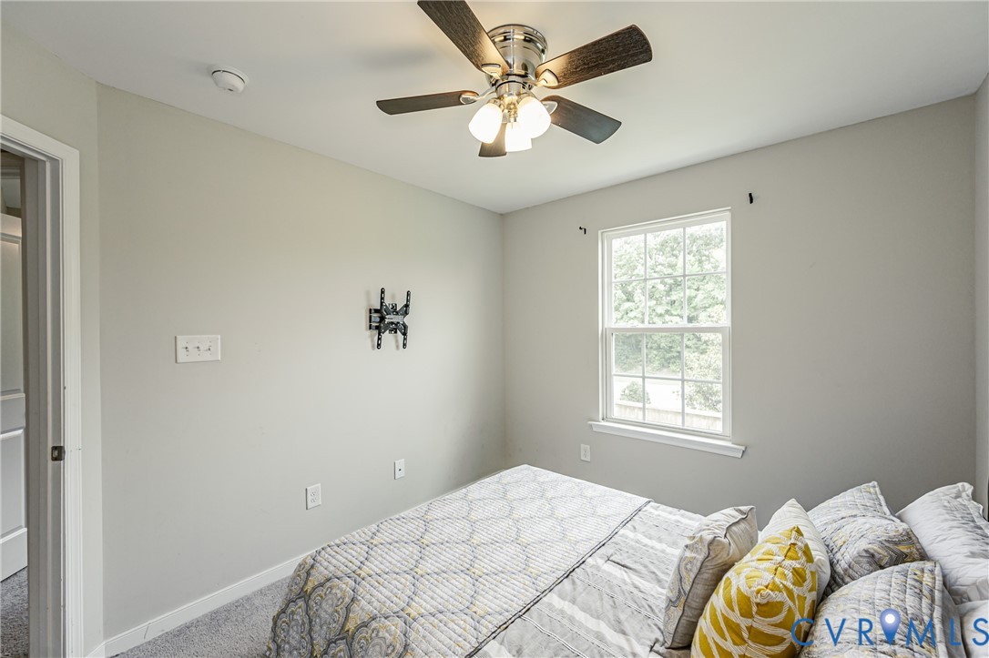 Interior room featuring light gray walls, a ceiling fan with integrated lighting, a double-hung window, and gray carpet flooring