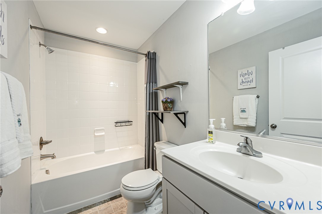 Bathroom featuring a white bathtub with subway tile surround, a built-in shower caddy, and brushed nickel fixtures
