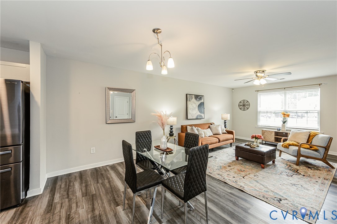 Open-concept living space featuring wood-finish flooring, a ceiling fan with integrated lighting, and a window with horizontal blinds