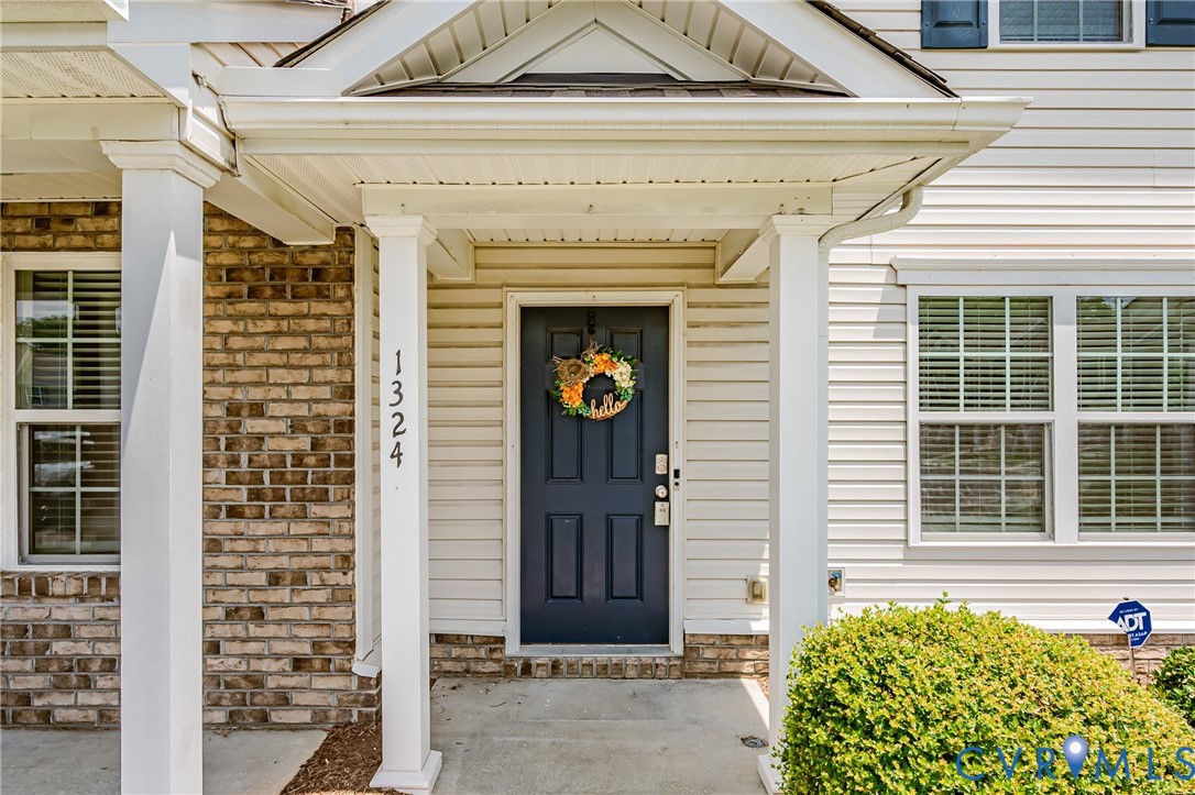 Covered entry featuring white columns and a dark-paneled front door