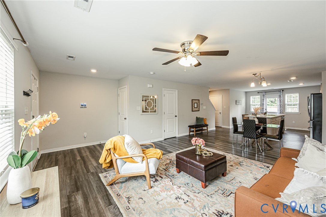 Spacious open-concept living area featuring wood-finish flooring, a ceiling fan, recessed lighting, and white trim