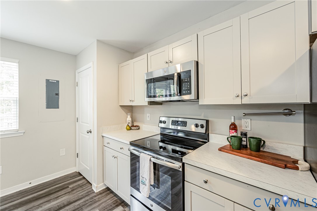 Kitchen featuring light-toned cabinetry with brushed nickel hardware, stainless steel appliances, and a wood-finish flooring