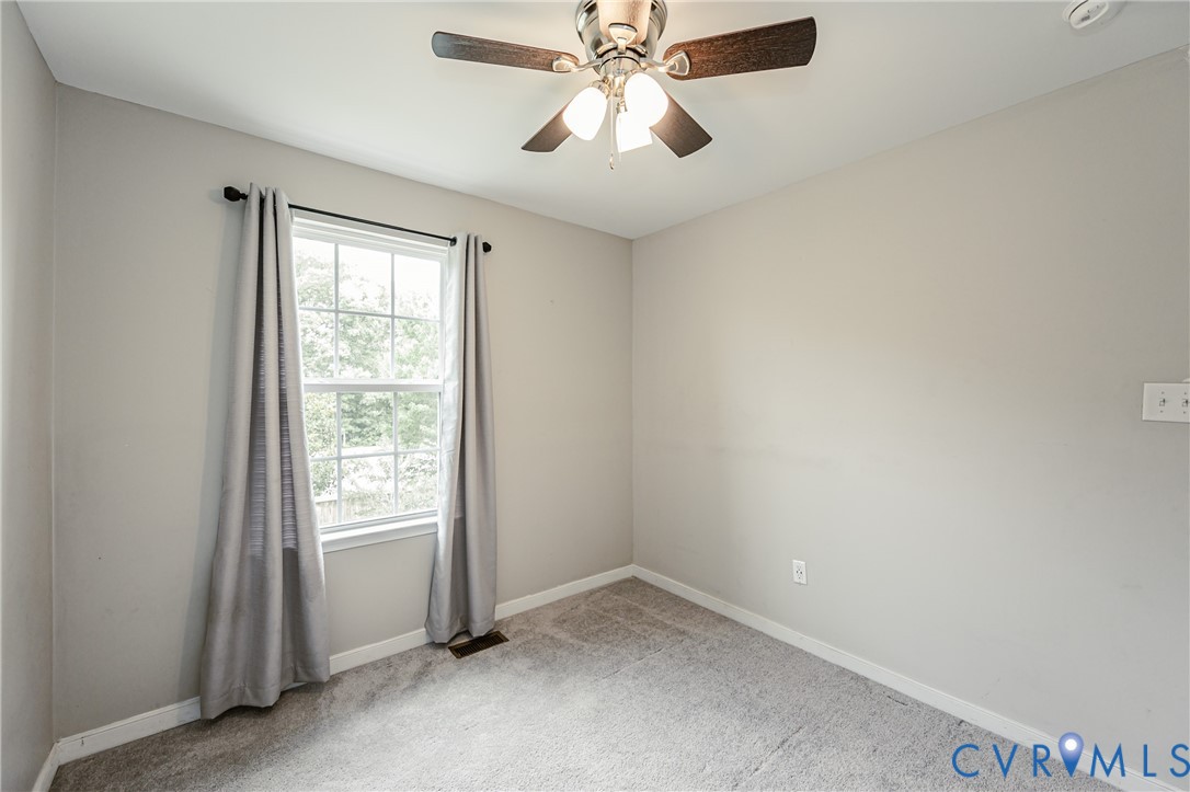 Neutral tone walls, ceiling fan with light fixture, double-hung window, and gray carpeting