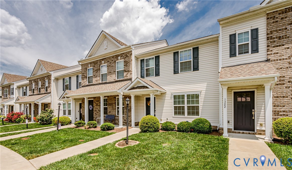 Two-story townhouse with white vinyl siding and brick facade accents