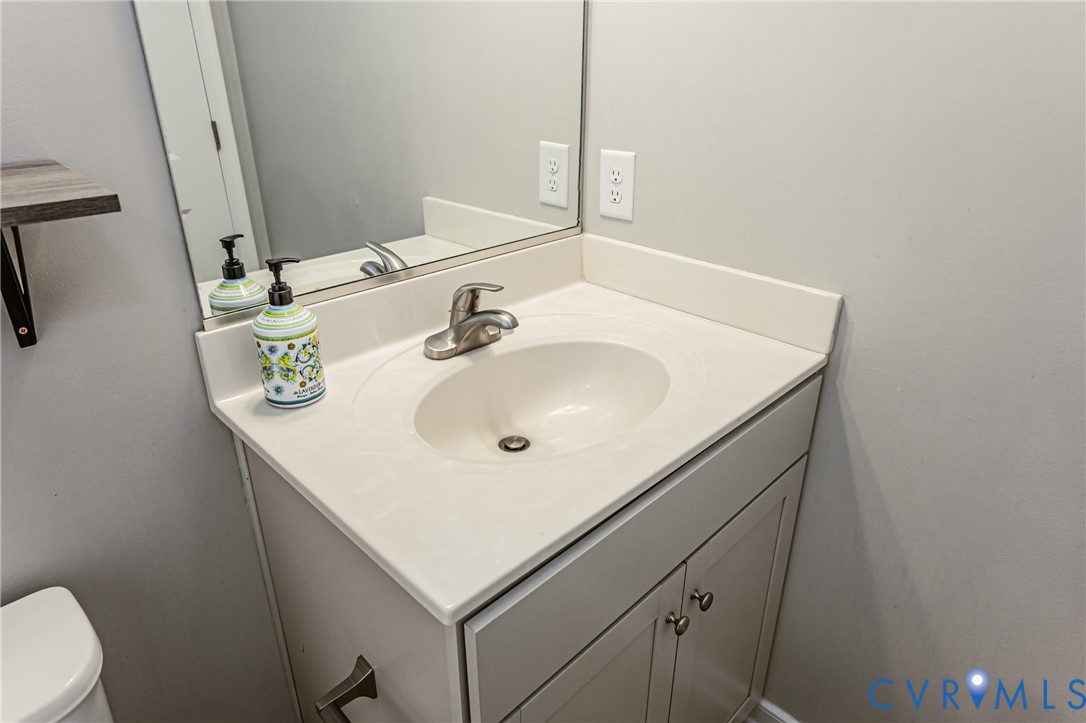 Bathroom vanity featuring a white countertop with an integrated sink, brushed nickel faucet, and a mirror