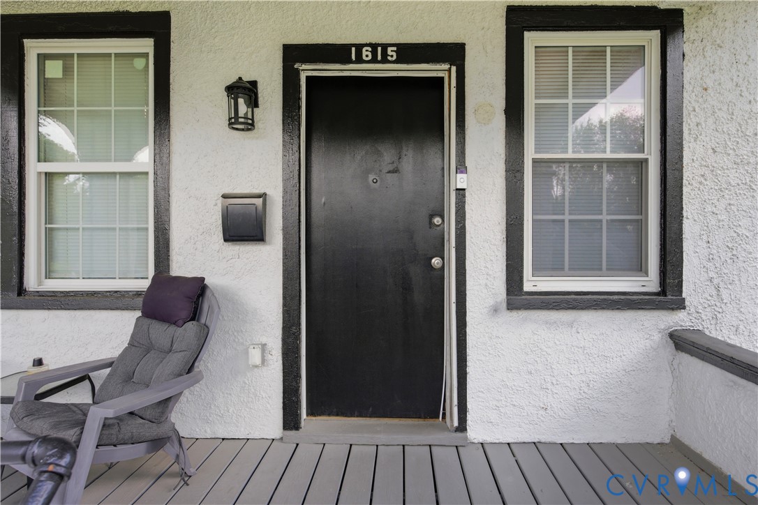 Front entry featuring a black door with contrasting white stucco siding and black trim Front entry featuring a black door with contrasting white stucco siding and black trim