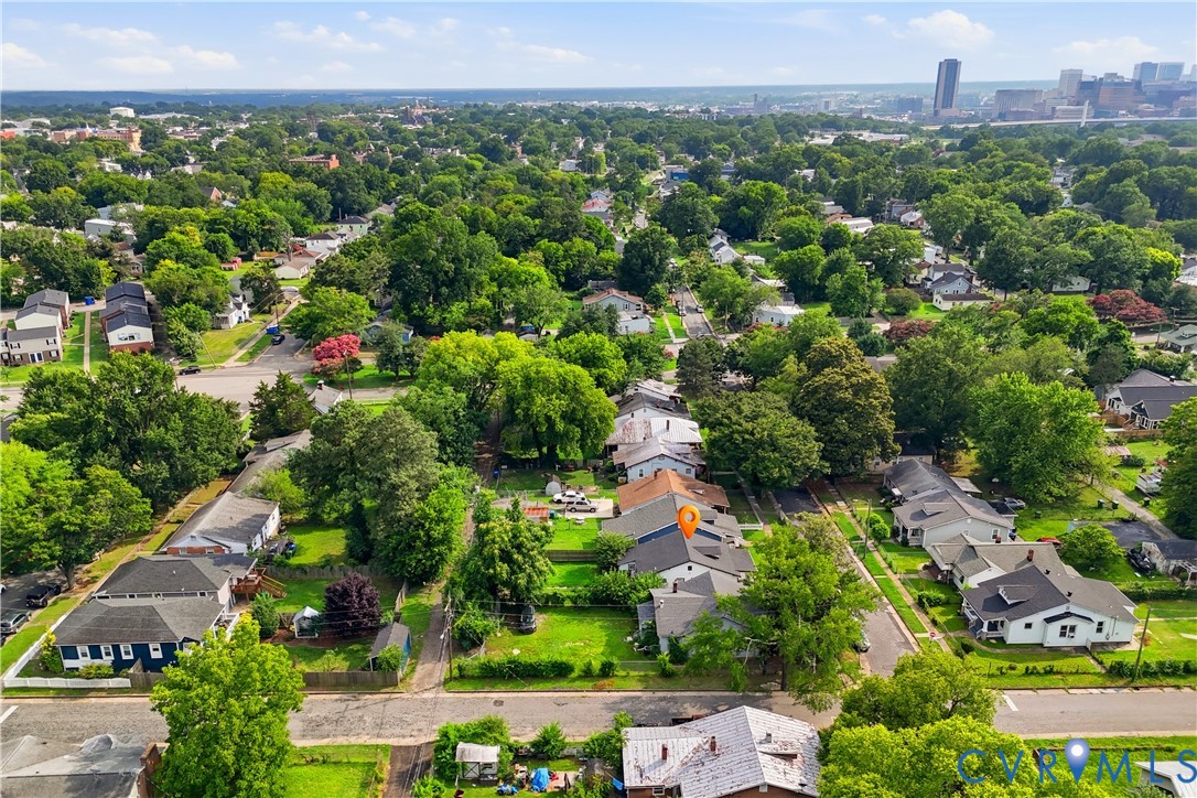 Residential streetscape featuring mature tree canopy, established homes, and urban background