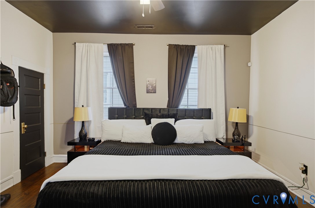 Hardwood flooring extends throughout this room, featuring a dark four-panel door with brass hardware