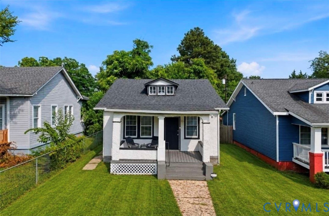 Stucco exterior featuring a covered front porch with dark gray steps and a dark front door