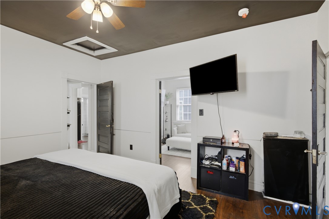 Spacious room featuring wood-finish flooring, a ceiling fan with integrated lighting, and a dark-painted ceiling