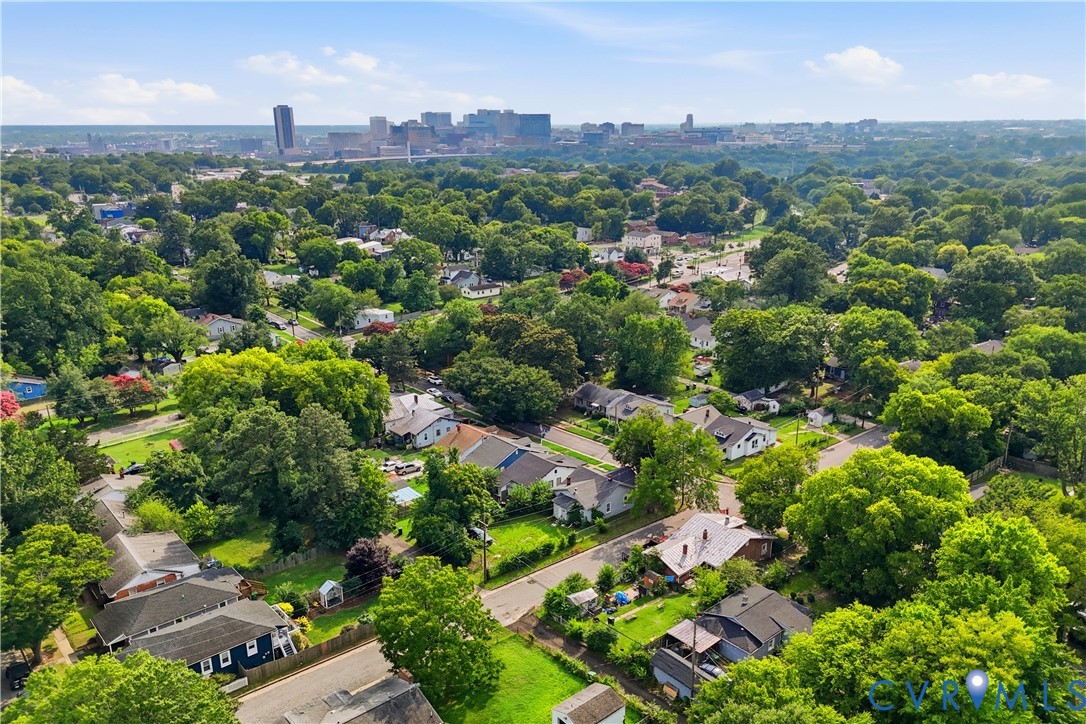 Aerial perspective showcasing a residential area with mature trees and a distant cityscape