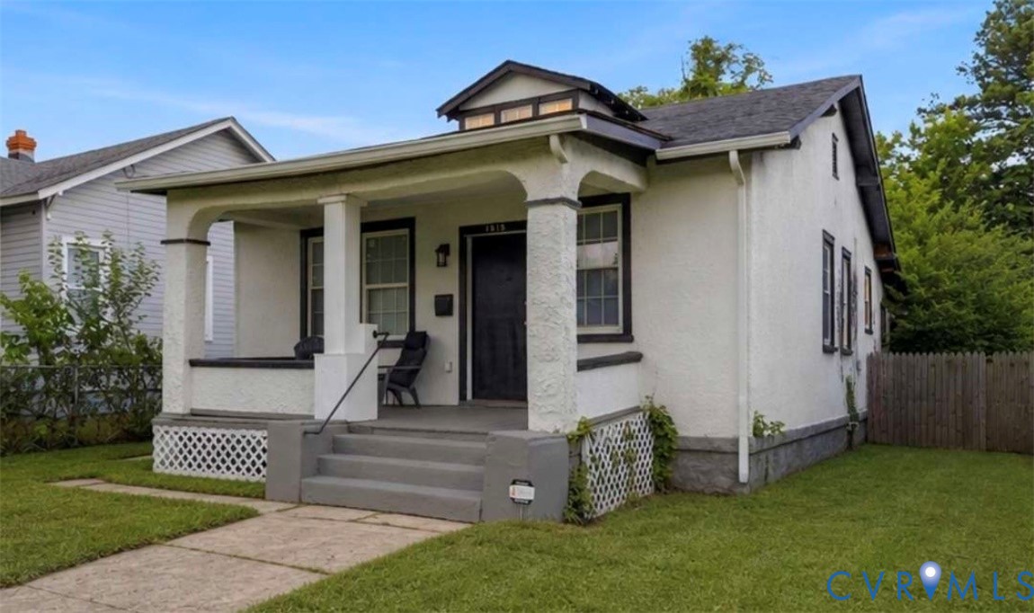Stucco exterior with a covered front porch featuring square columns and a black metal handrail Stucco exterior with a covered front porch featuring square columns and a black metal handrail