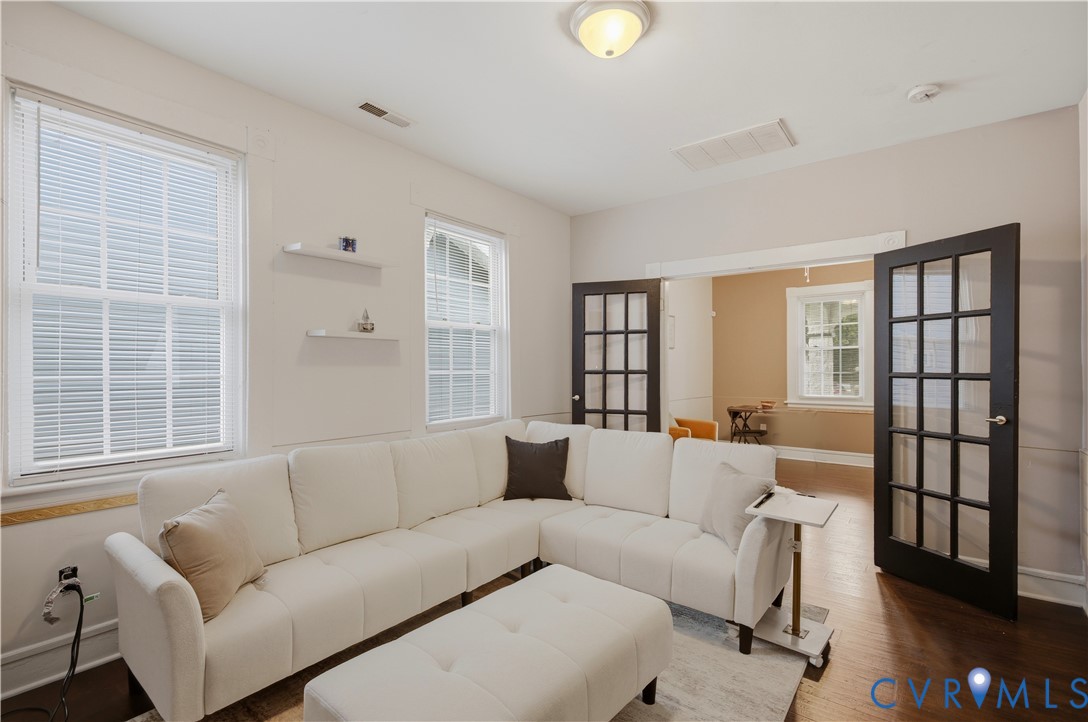Interior living space featuring dark wood-finish flooring, light-toned walls, and multiple windows with blinds