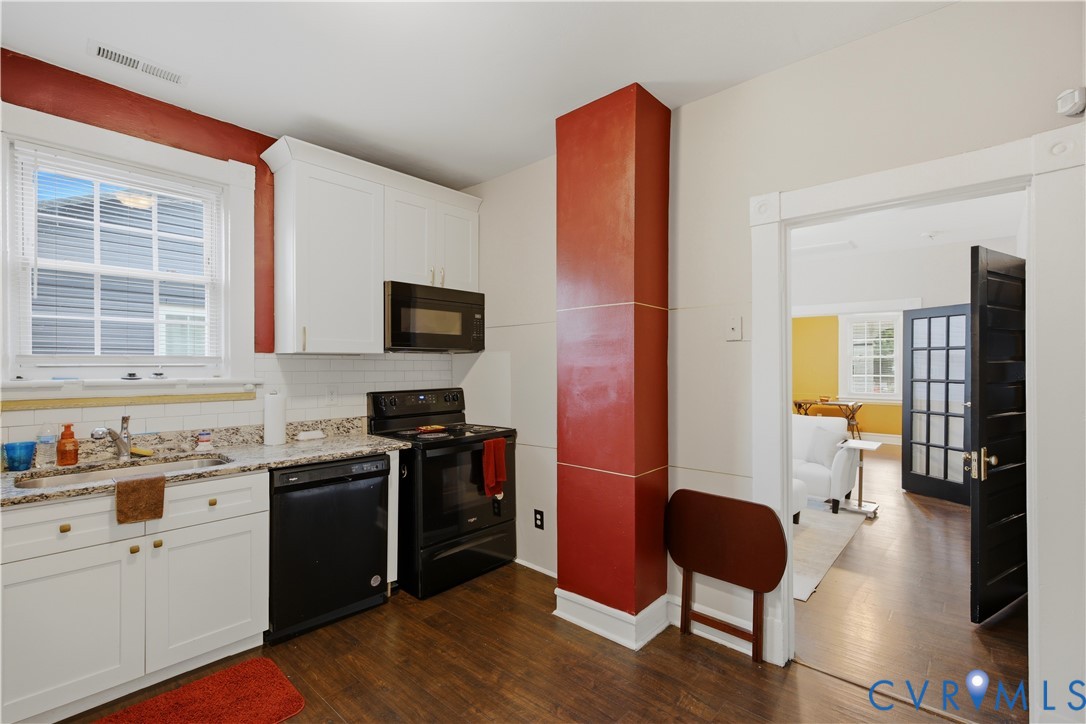 Compact kitchen featuring wood-finish flooring, white cabinetry, and granite-style countertops