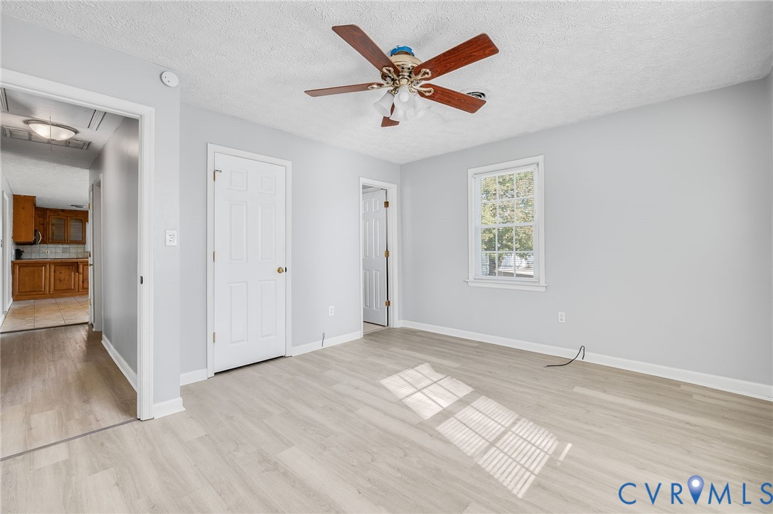 Light wood-finish flooring with a ceiling fan, a window, and light gray wall paint