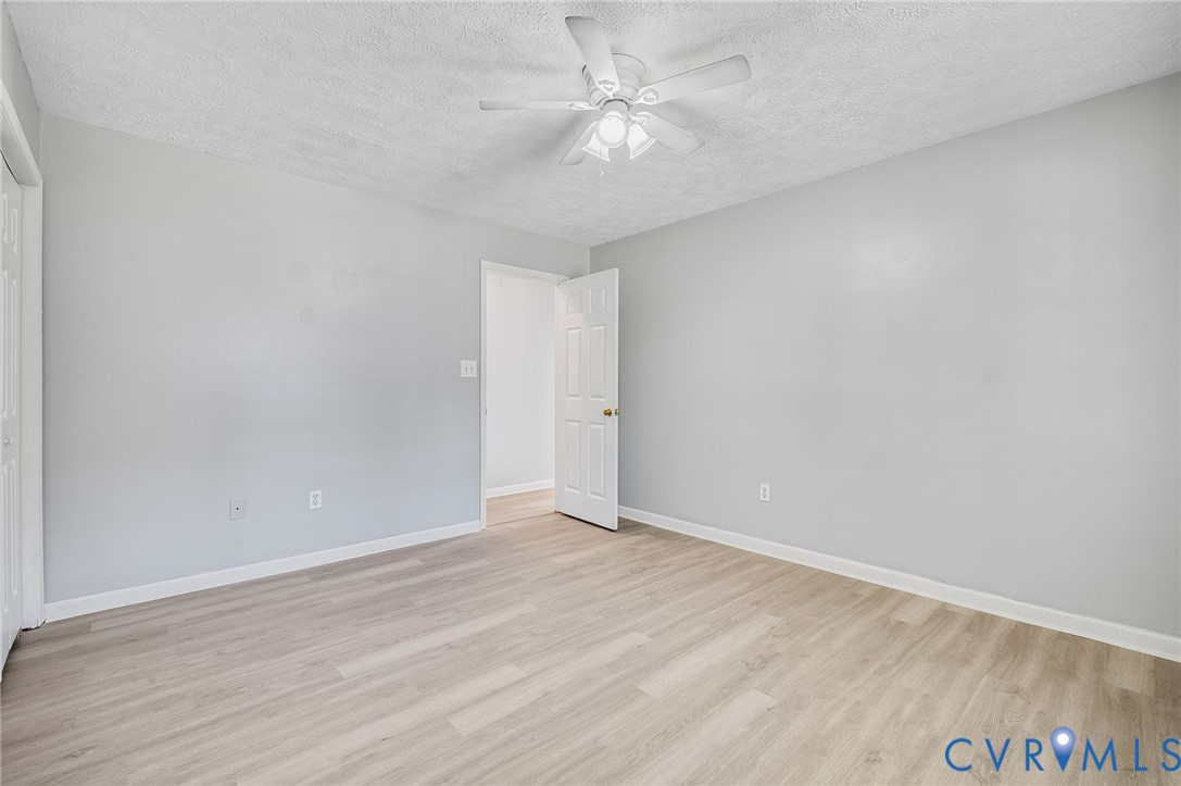 Light-toned wood-finish flooring, white walls, and a ceiling fan with integrated lighting