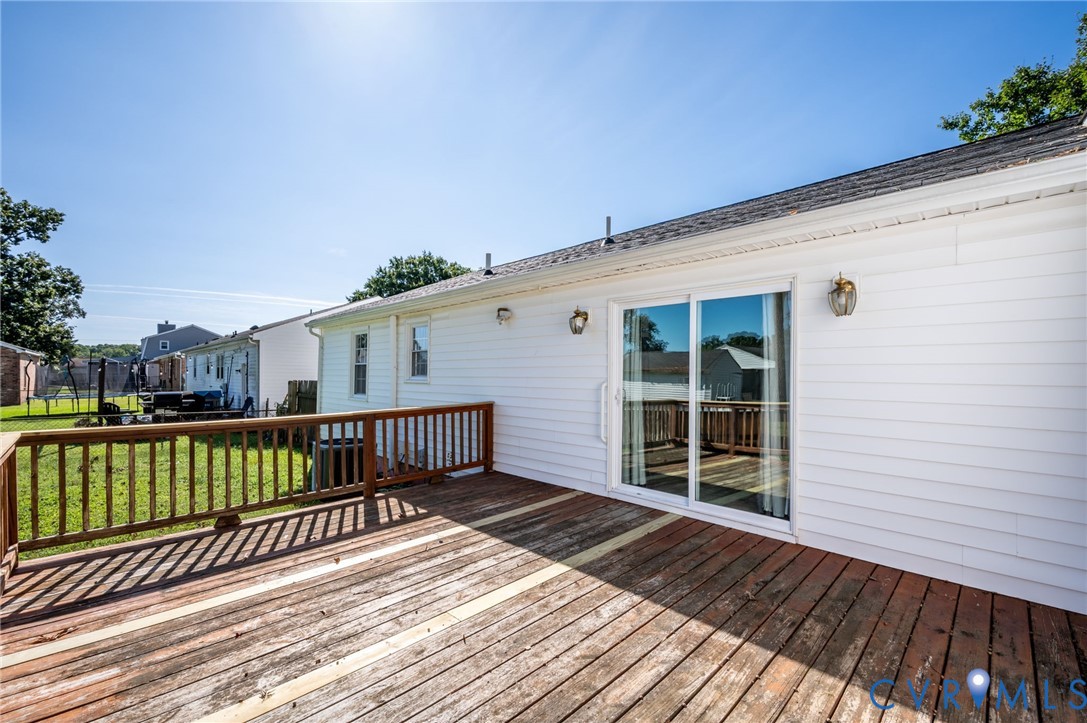 Expansive outdoor wood deck with wood railing, white siding, and sliding glass door access