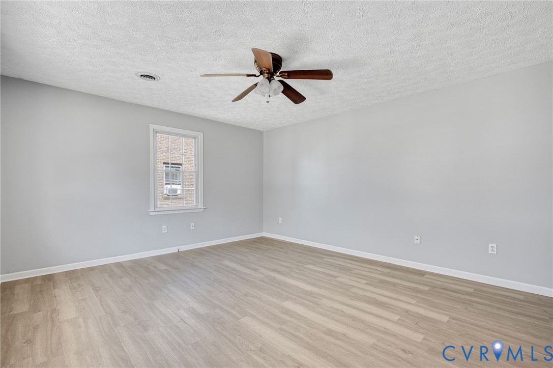 Light-toned wood-finish flooring, neutral wall paint, and a ceiling fan with integrated lighting