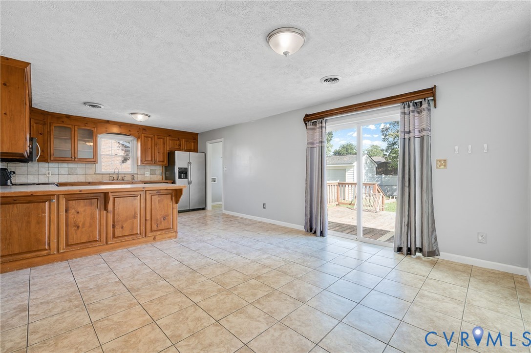 Kitchen with wood cabinetry, tile flooring, and a sliding glass door