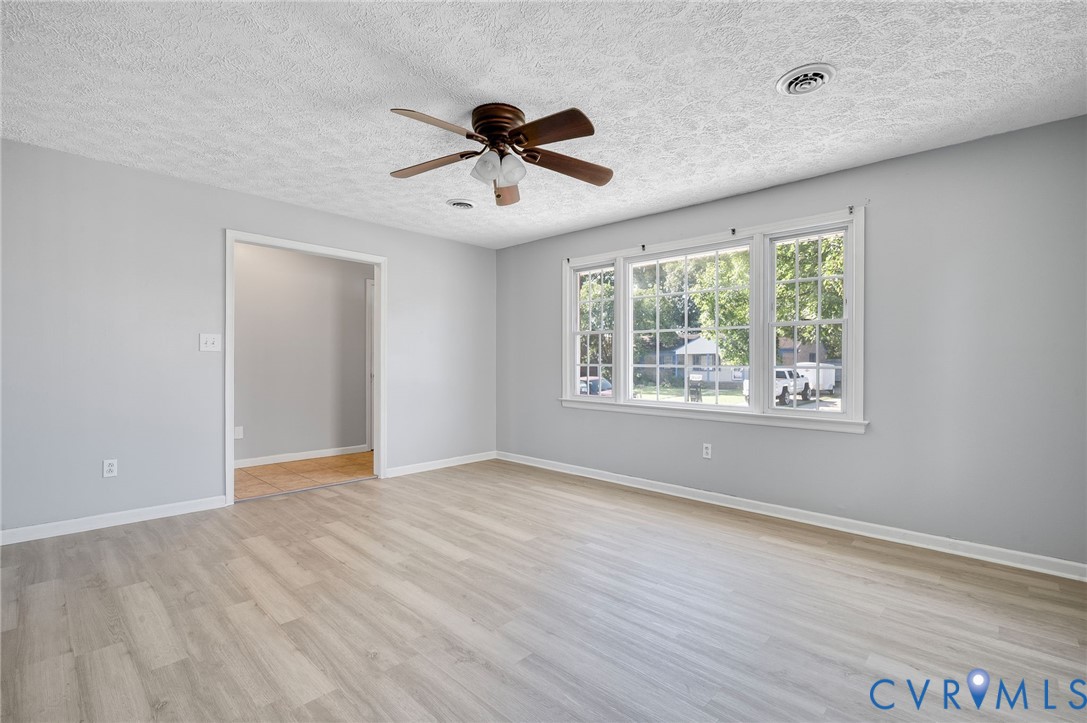 Light wood-finish flooring, white trim, and a ceiling fan with integrated lighting