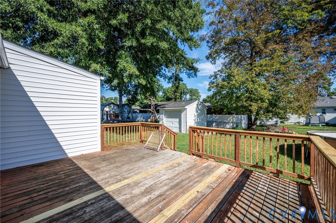 Expansive outdoor wood deck with natural wood railings, overlooking a grassy yard with mature trees
