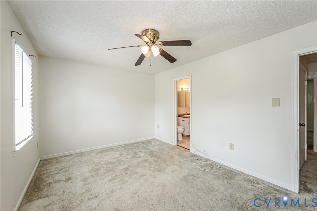 Spacious room featuring neutral carpeting, a ceiling fan with integrated lighting, and a single window with blinds