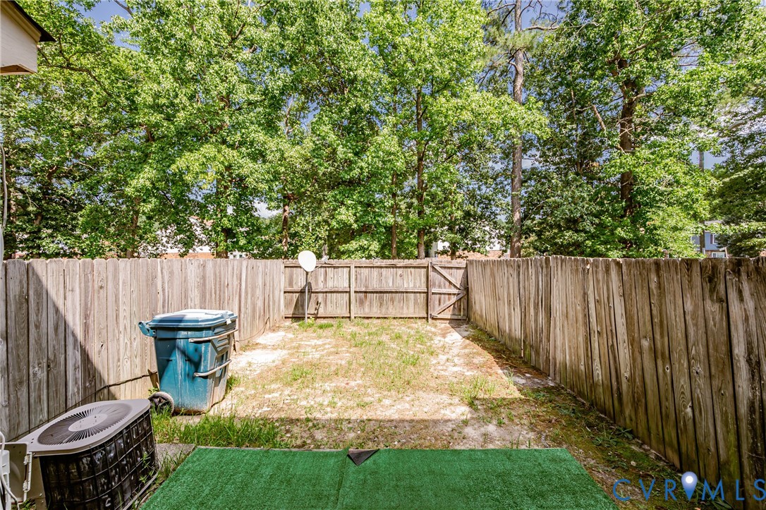 Fenced backyard with mature trees providing a natural backdrop