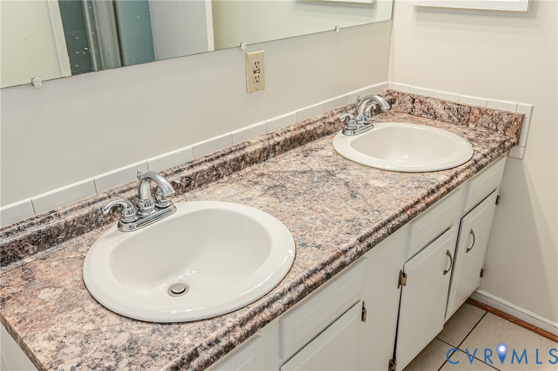Dual vanity featuring white oval sinks, chrome faucets, and a patterned countertop with an integrated backsplash