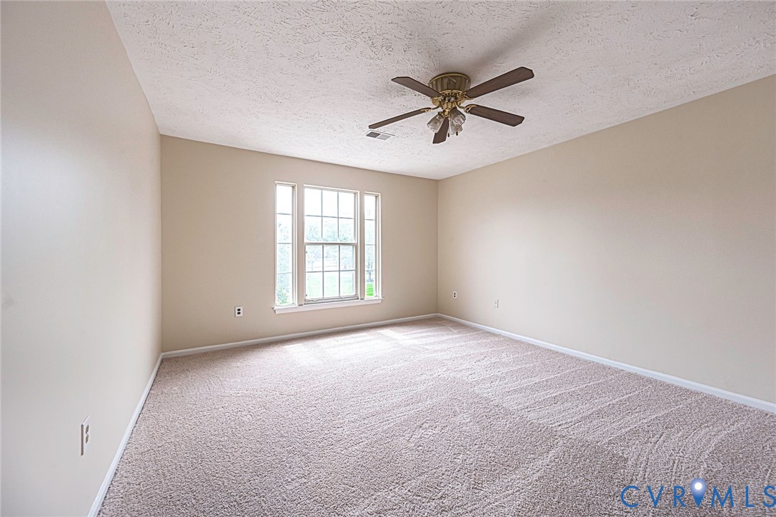 Carpeted room featuring a ceiling fan, a multi-pane window, and light-toned wall paint