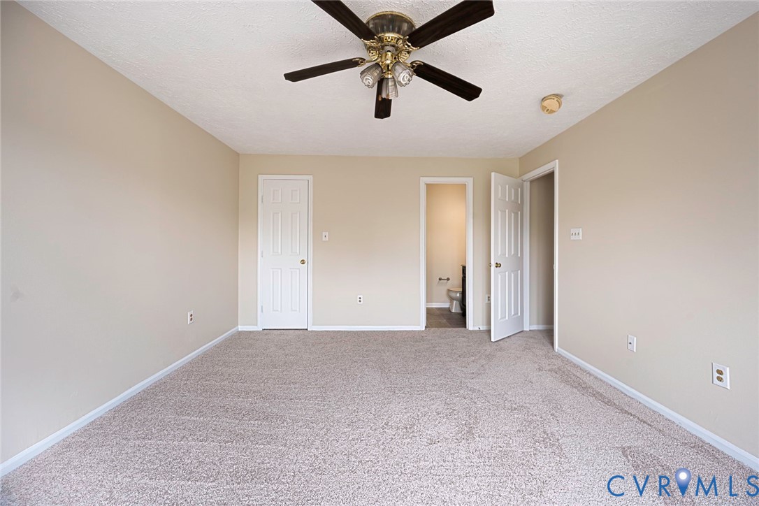 Carpeted room featuring a ceiling fan with light fixture, neutral wall paint, white baseboards, and two paneled interior doors