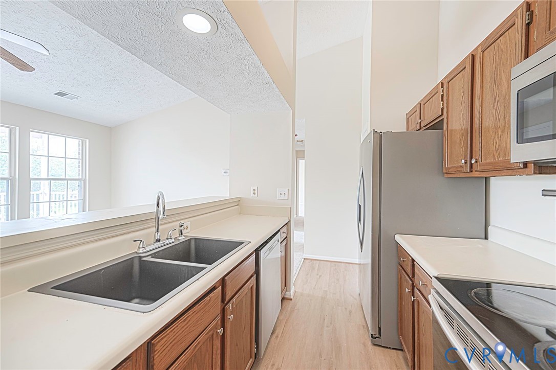 Kitchen featuring a dual basin sink, light-toned countertops, and wood-finish cabinetry