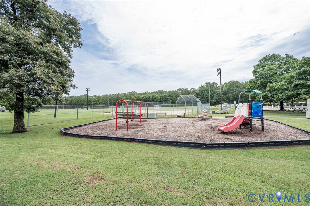 Community playground featuring a swing set, slide, and teeter-totter on a wood chip base