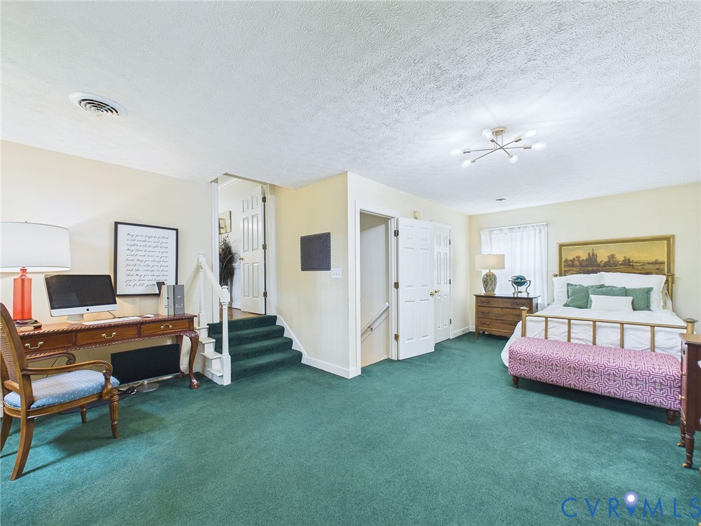 Spacious room featuring green carpeting, dual entryways, and a built-in staircase