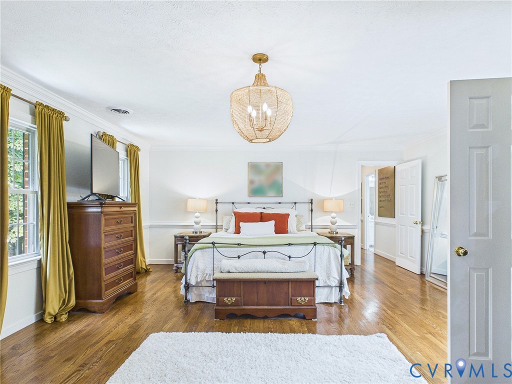 Spacious room featuring wood-finish flooring, white walls, and bright natural light from multiple windows