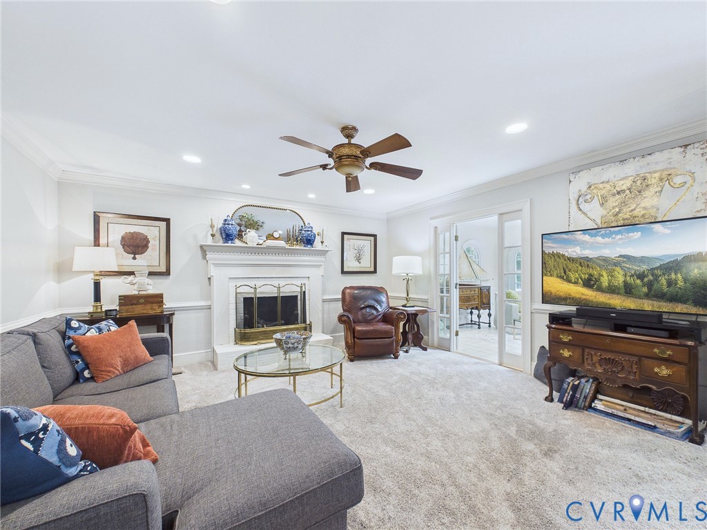 Living area featuring a white fireplace with a brass firebox, recessed lighting, crown molding, and light-colored carpeting