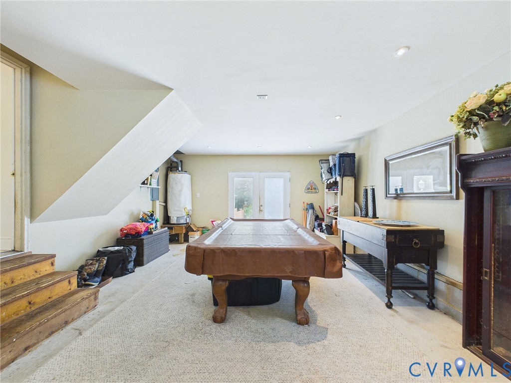 Lower level recreation space featuring neutral carpeting, recessed ceiling lighting, and a partial staircase