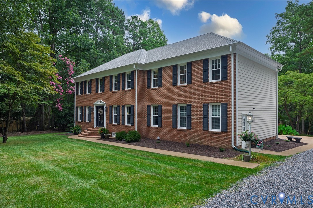 Traditional Colonial-style residence featuring a brick facade, white siding, and a gabled roof Traditional Colonial-style residence featuring a brick facade, white siding, and a gabled roof