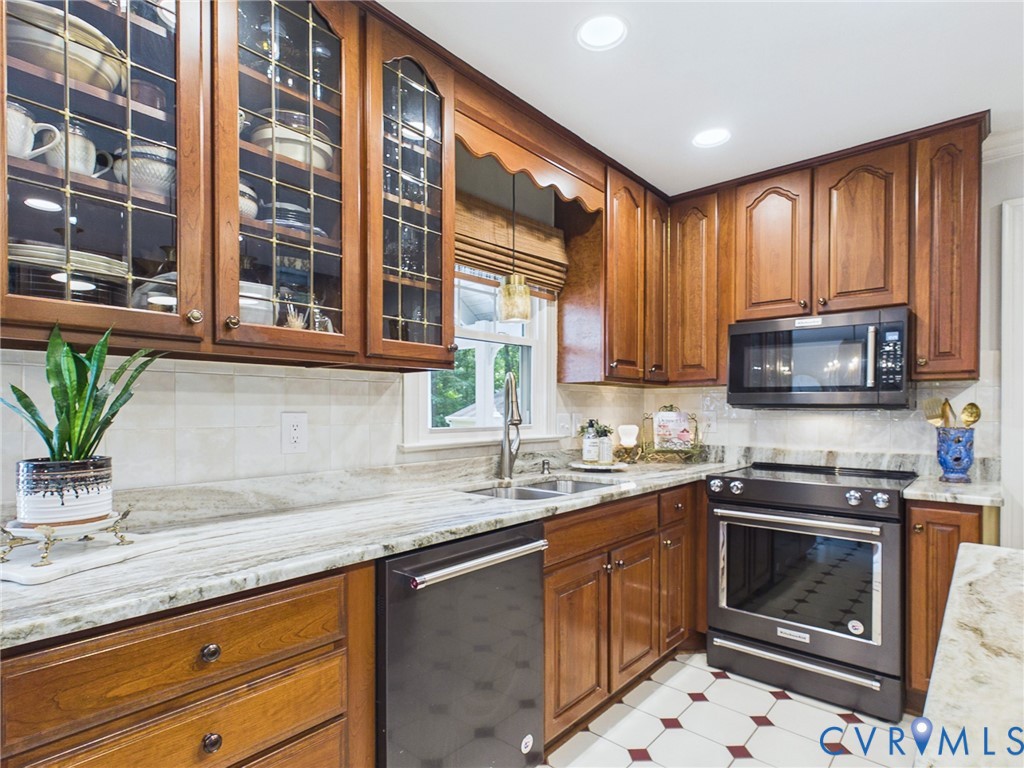 Kitchen featuring wood-finish cabinetry, patterned flooring, light-toned countertops, a stainless steel sink, and built-in appliances