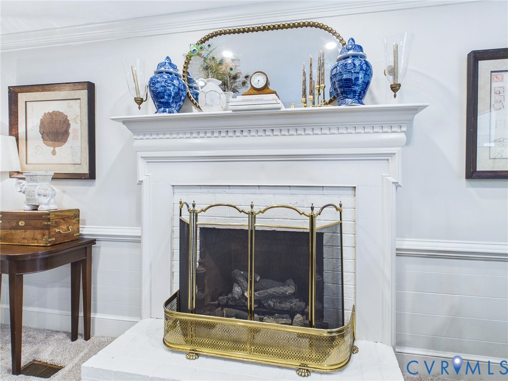 Fireplace featuring a white mantel, white brick hearth, and brass fire screen