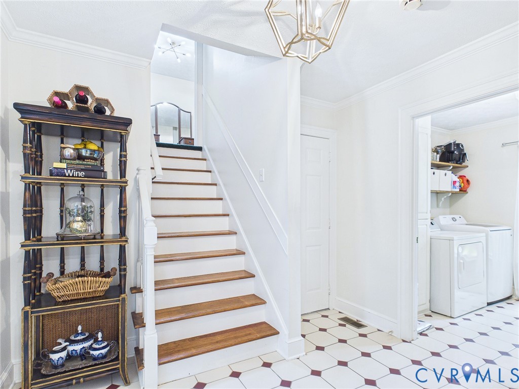 Foyer featuring a geometric pattern tile floor, wood tread staircase with white risers and railing, a built-in shelving unit, and an overhead decorative light fixture