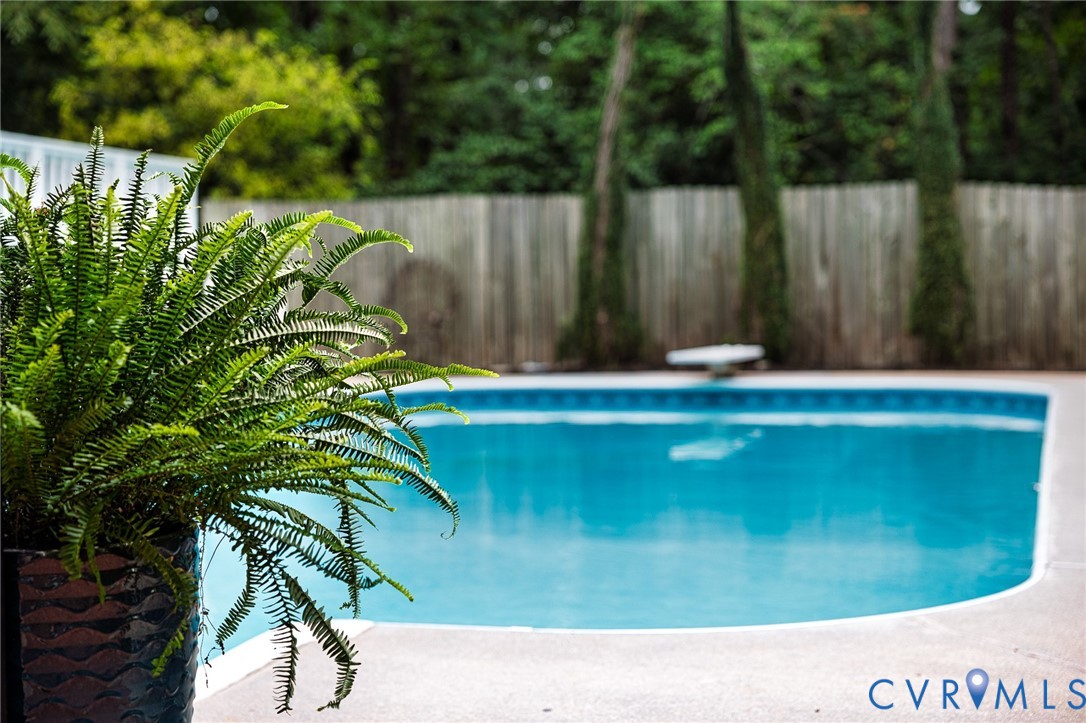 In-ground swimming pool with a blue tile border and a white diving board In-ground swimming pool with a blue tile border and a white diving board