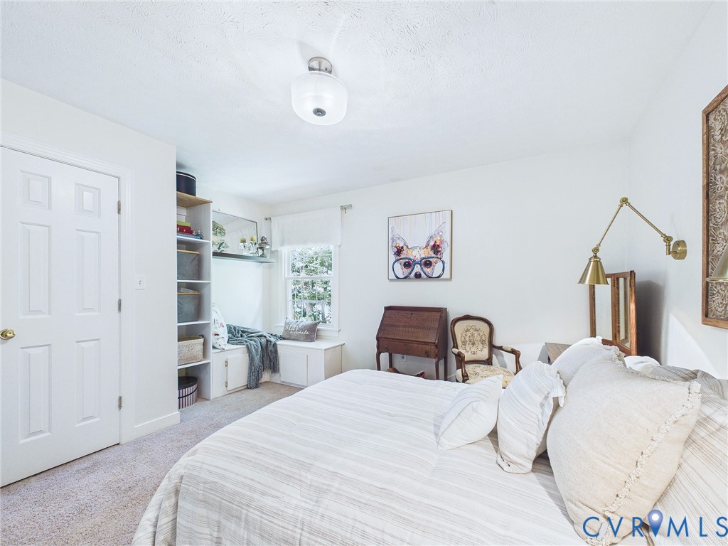 Light-filled room featuring a built-in window bench, integrated shelving, neutral wall colors, and wall-to-wall carpeting