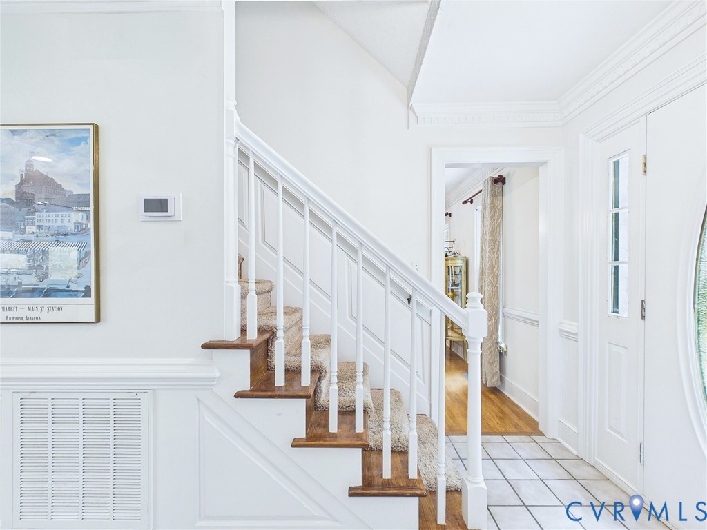 Classic staircase featuring wood treads with carpet runners and white balusters