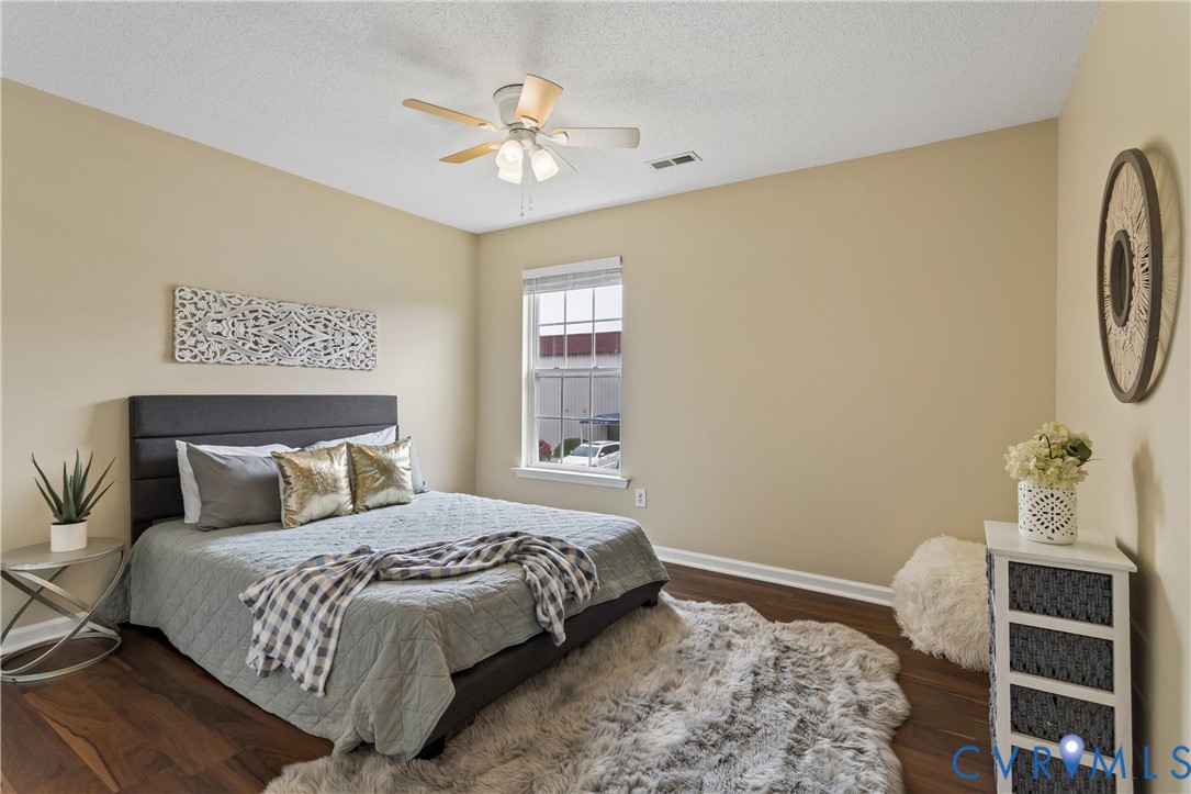 Bedroom featuring wood-finish flooring, a double window with blinds, a ceiling fan with integrated lighting, and neutral wall tones