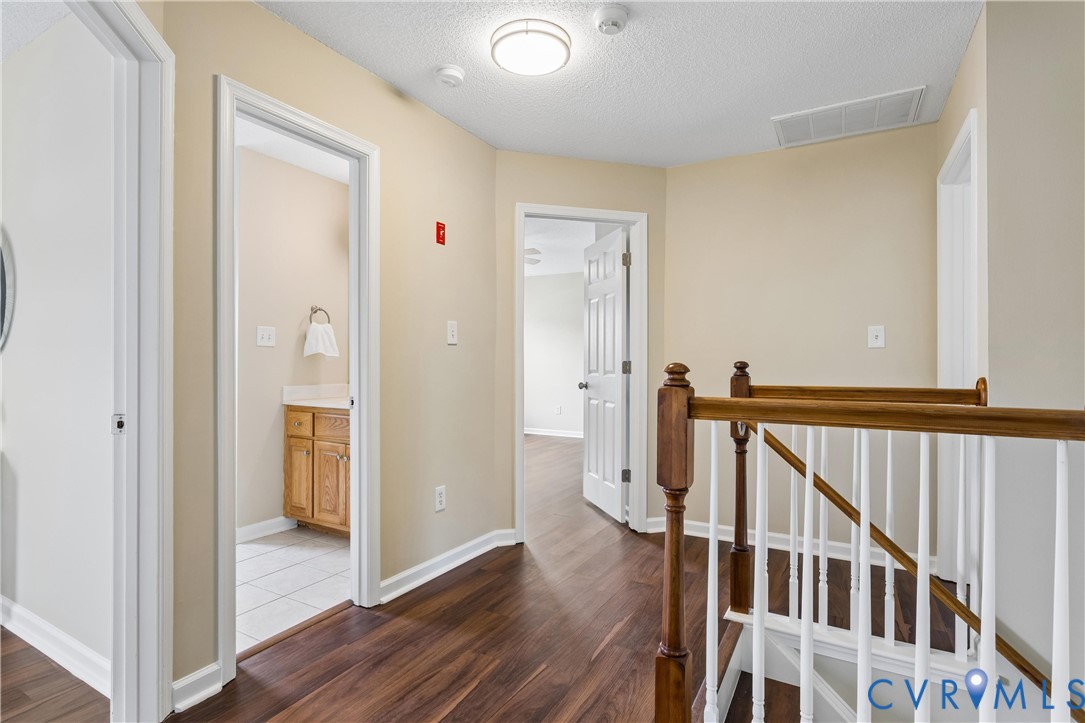 Second-story hallway featuring wood-finish flooring, light tan wall paint, and white trim