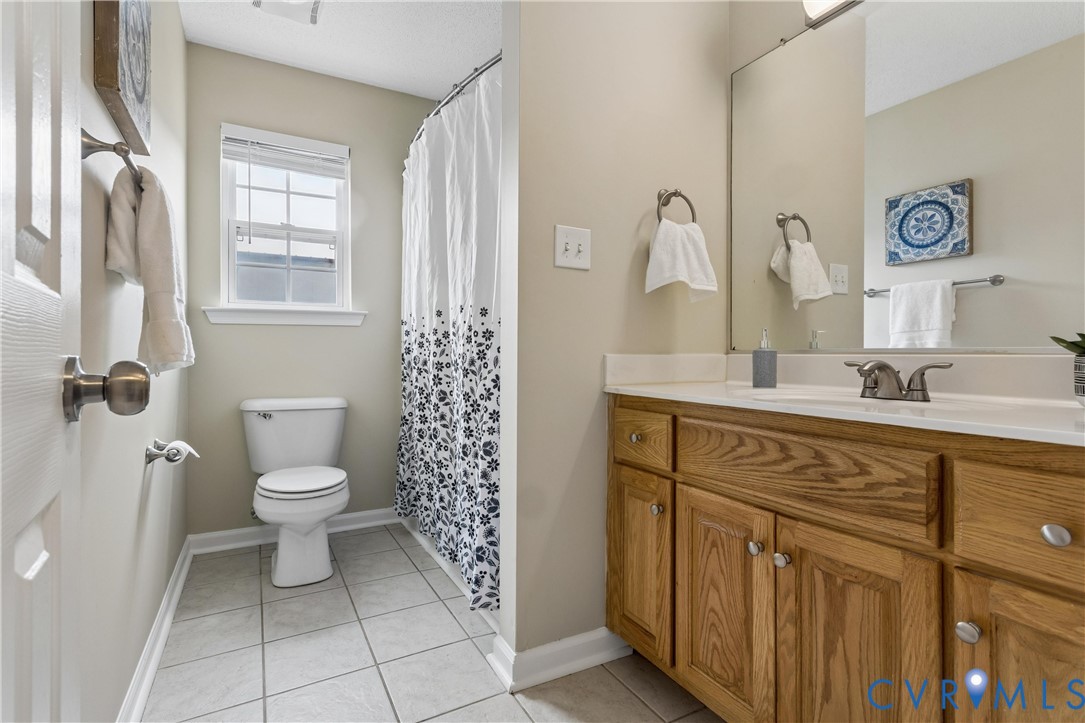 Bathroom featuring a wood-finish vanity with a white countertop and a rectangular sink