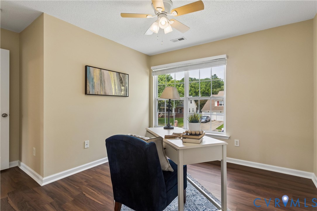 Room featuring wood-finish flooring, a ceiling fan with integrated lighting, and a large window with white blinds