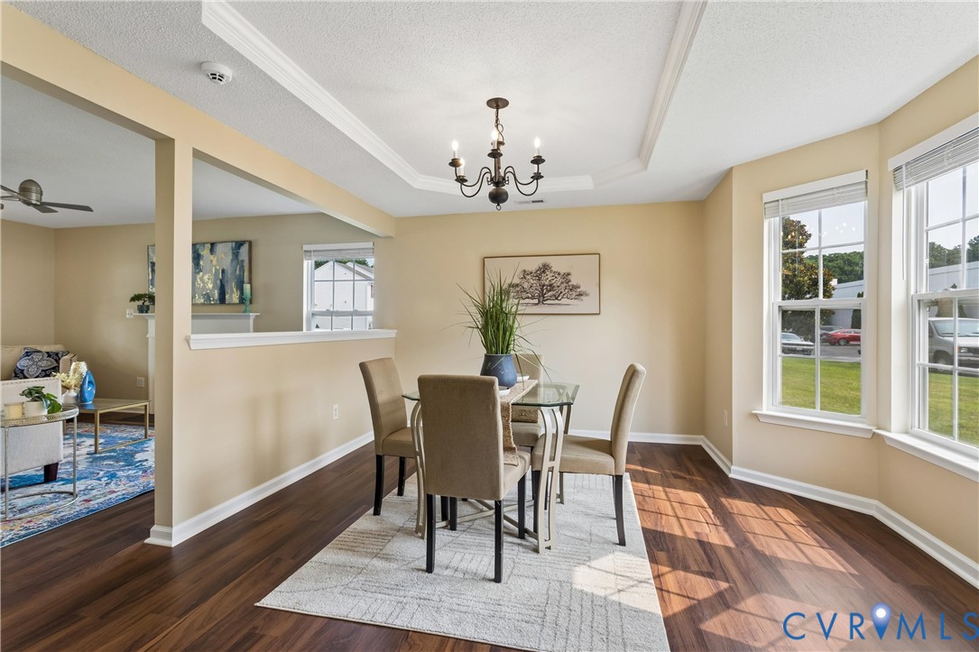 Dining area featuring wood-finish flooring, a tray ceiling, and a chandelier