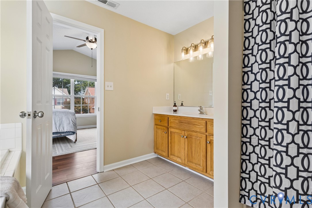 Bathroom vanity with a single sink, light wood cabinetry, and a light-toned countertop