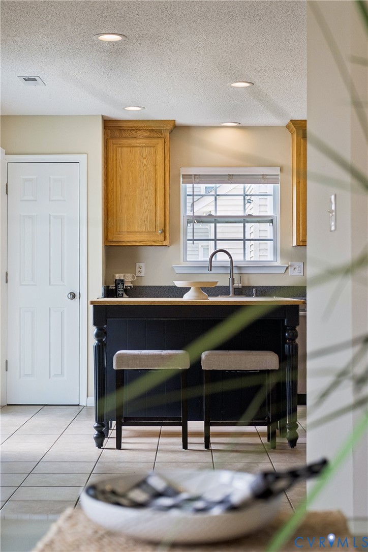 Kitchen island featuring a wood-finish countertop and dark cabinetry with turned legs